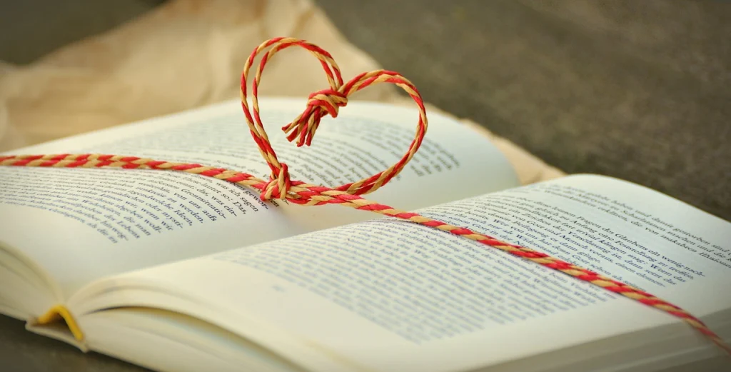 This image shows an open book with a heart-shaped ribbon on top.